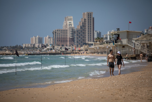 Israelis walk along Dado Beach in Haifa on May 16, 2021. (credit: SHIR TOREM/FLASH90)