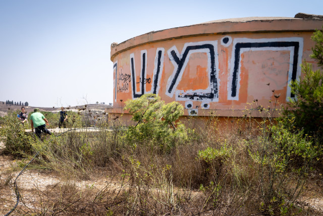  Visitors walk by the water tower on the ruins of the evacuated settlement of Homesh on August 27, 2019. (credit: HILLEL MAEIR/FLASH90)