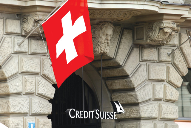  SWITZERLAND’S NATIONAL flag flies above the logo of Swiss bank Credit Suisse at its headquarters in Zurich.  (credit: ARND WIEGMANN / REUTERS)