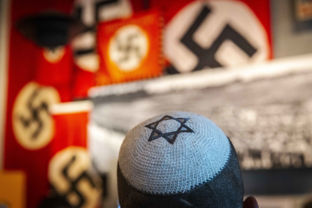  Visitors seen standing next to a display of swastika banners at the Yad Vashem Holocaust Memorial museum in Jerusalem on April 26, 2022, ahead of Israeli Holocaust Remembrance Day.  (credit: OLIVIER FITOUSSI/FLASH90)