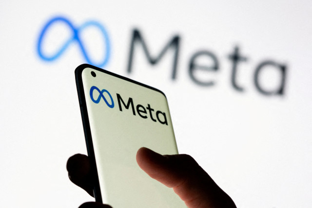  Woman holds smartphone with Meta logo in front of a displayed Facebook's new rebrand logo Meta in this illustration picture taken October 28, 2021.  (credit: REUTERS/DADO RUVIC/ILLUSTRATION)