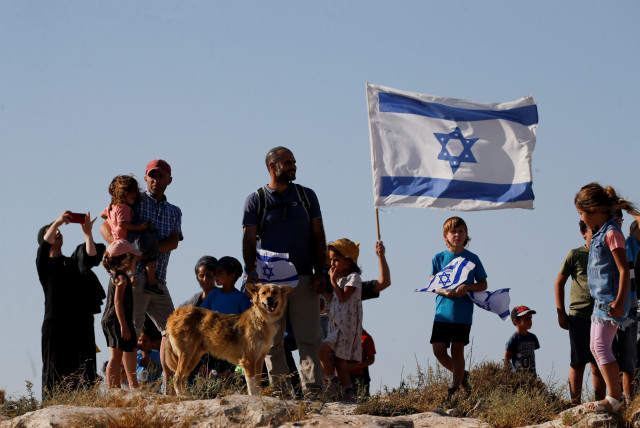  Jewish settlers look on during a march near Hebron in the West Bank, June 21, 2021 (credit: REUTERS/MUSSA QAWASMA)