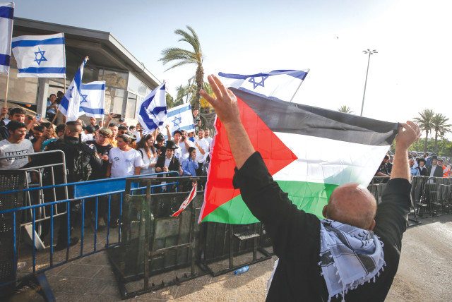  A MAN displays a Palestinian flag across from celebrants holding Israeli flags in Jerusalem’s Old City during Jerusalem Day festivities, last week. (credit: JAMAL AWAD/FLASH90)