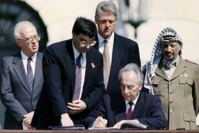  THEN-FOREIGN MINISTER Shimon Peres signs the Oslo Accords, witnessed by (from R) PLO chairman Yasser Arafat, prime minister Yitzhak Rabin and US president Bill Clinton, at the White House, Sept. 13, 1993. (credit: GARY HERSHORN/REUTERS)