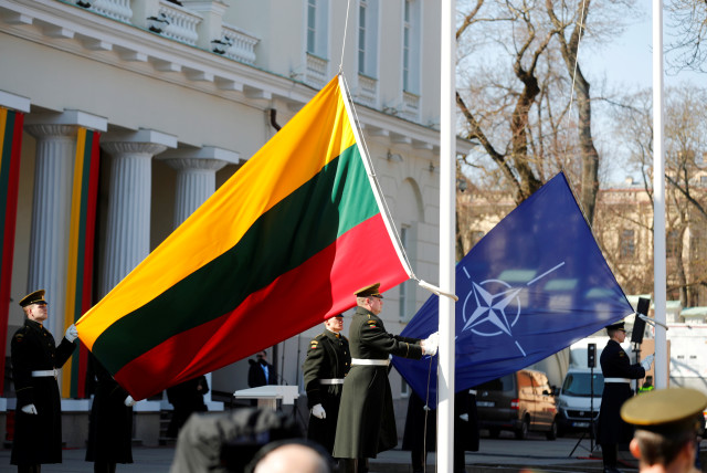  Lithuanian Army soldiers hold Lithuanian and NATO flags during the celebration of the 15th anniversary of Lithuania's membership in NATO in Vilnius, Lithuania March 30, 2019. (credit: Ints Kalnins/Reuters)
