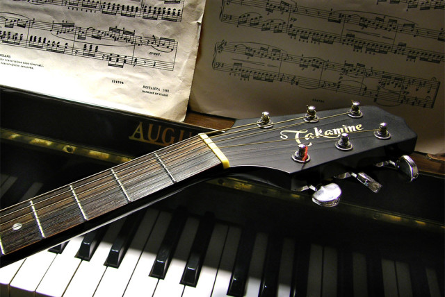  A guitar lies across a piano. (credit: FLICKR)