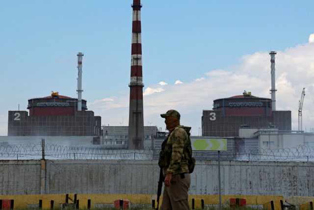 A serviceman with a Russian flag on his uniform stands guard near the Zaporizhzhia Nuclear Power Plant in the course of Ukraine-Russia conflict outside the Russian-controlled city of Enerhodar in the Zaporizhzhia region, Ukraine August 4, 2022. (photo credit: REUTERS/Alexander Ermochenko/File Photo)