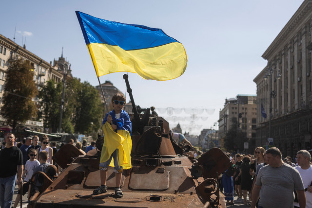 A boy waves a national flag atop of armoured personal carrier at an exhibition of destroyed Russian military vehicles and weapons, dedicated to the upcoming country's Independence Day, amid Russia's attack on Ukraine, in the centre of Kyiv, Ukraine August 21, 2022. (credit: REUTERS/VALENTYN OGIRENKO)