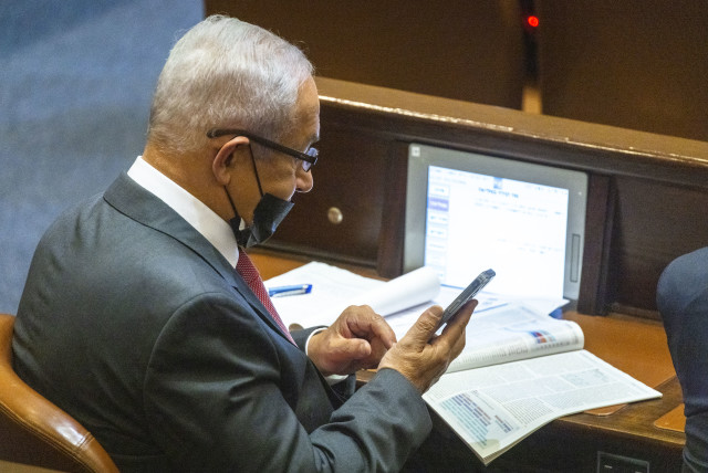  Benjamin Netanyahu checking his phone at the Knesset plenum, October 27, 2021 (credit: OLIVIER FITOUSSI/FLASH90)