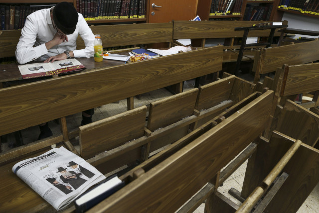  A young ultra orthodox Jewish man seen reading a newspaper in between studies at the Yeshiva Ateret Israel, in Jerusalem, September 2, 2013 (credit: NATI SHOHAT/FLASH90)