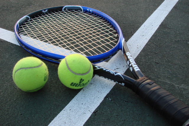 A tennis racket and two tennis balls on a court (credit: VLADSINGER/CC BY-SA 3.0 (http://creativecommons.org/licenses/by-sa/3.0/)/VIA WIKIMEDIA COMMONS)