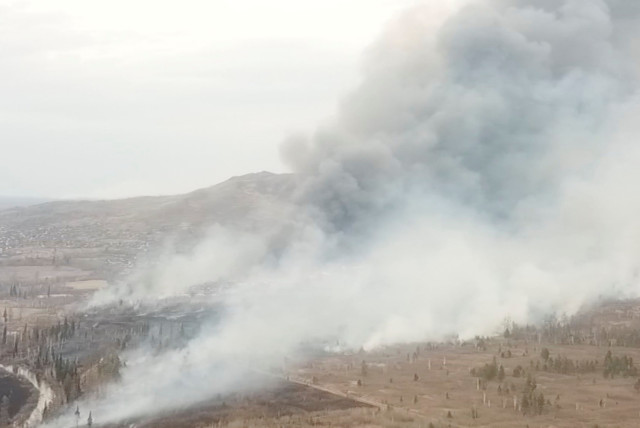  Smoke from a wildfire rises above the village of Morgudon in the Irkutsk Region, Russia, in this still image taken from a video. Video taken May 7, 2022. (credit: REUTERS TV via REUTERS)