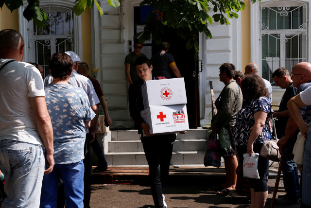 Residents stand in line to collect humanitarian aid at a Red Cross distribution point, as Russia's attacks on Ukraine continues, in Mykolaiv, Ukraine, June 10, 2022. (credit: REUTERS/EDGAR SU)