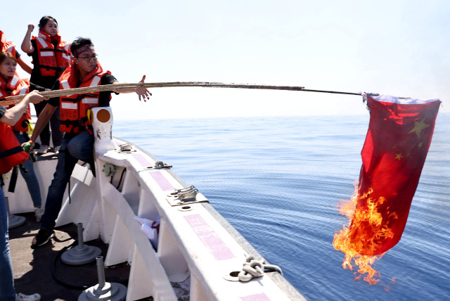 Members of the pro-independence Taiwan Statebuilding Party burn a Chinese flag on boat trip in the Taiwan Strait in Kaohsiung, Taiwan, October 1, 2022. (credit: REUTERS/ANN WANG)