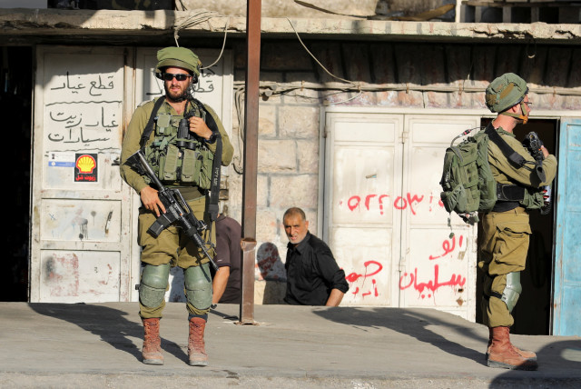  Israeli soldiers stand while stationed outside a Palestinian shop in Huwara, Israeli-occupied West Bank, May 26, 2022. (credit: RANEEN SAWAFTA/ REUTERS)