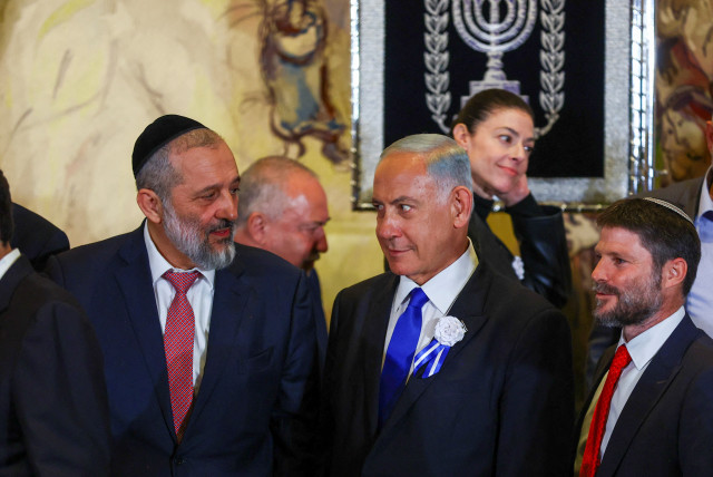  Benjamin Netanyahu looks at Shas leader MK Aryeh Deri as they stand with other members of the new Israeli parliament after their swearing-in ceremony in Jerusalem November 15, 2022.  (credit: RONEN ZVULUN/REUTERS)