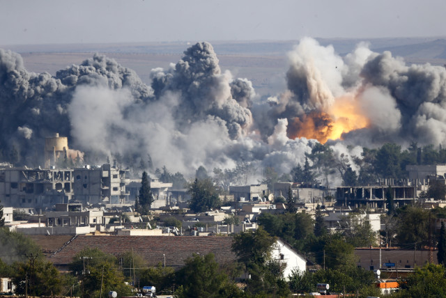 Smoke rises over Syrian town of Kobani after an airstrike, as seen from the Mursitpinar border crossing on the Turkish-Syrian border in the southeastern town of Suruc in Sanliurfa province, October 18, 2014. (credit: REUTERS/KAI PFAFFENBACH)