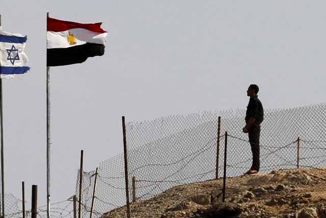  An Egyptian soldier stands near the Egyptian national flag and the Israeli flag at the Taba crossing between Egypt and Israel, about 430 km (256 miles) northeast of Cairo, October 26, 2011 (credit: MOHAMED ABD EL-GHANY/REUTERS)