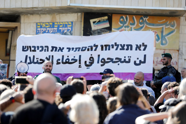  A banner is seen as Israeli activists take part in a tour for a group called Breaking the Silence, in Hebron in the West Bank December 2, 2022. The banner reads: ''You will not succeed in hiding occupation.'' (credit: REUTERS/MUSSA QAWASMA)