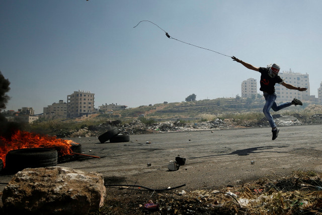  A Palestinian protester uses a sling to hurl stones towards Israeli troops during clashes at a protest in support of Palestinian prisoners on hunger strike in Israeli jails, near the Jewish settlement of Beit El, near the West Bank city of Ramallah May 11, 2017 (credit: REUTERS/MOHAMAD TOROKMAN)
