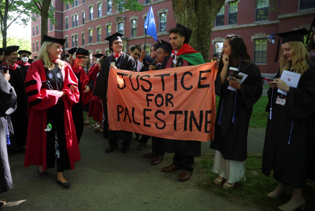 Estudiantes que se gradúan sostienen un cartel en el que se lee ''Justicia para Palestina'' durante los 371º Ejercicios de Graduación de la Universidad de Harvard en Cambridge, Massachusetts, EE.UU., 26 de mayo de 2022 (crédito: BRIAN SNYDER/REUTERS)