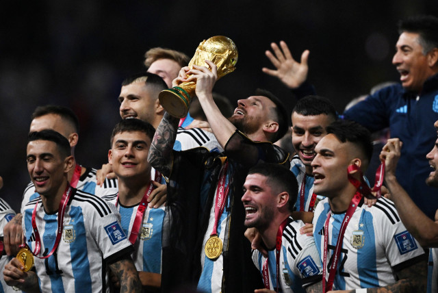Argentina's Lionel Messi lifts the World Cup trophy alongside teammates as they celebrate after winning the World Cup,  December 18, 2022. (credit: REUTERS/DYLAN MARTINEZ)