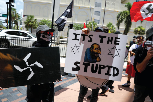  Demonstrators hold antisemitic symbols and signs as they protest outside the Tampa Convention Center, where Turning Point USA’s Student Action Summit was being held, in Tampa, Florida on July 23, 2022.  (credit: MARCO BELLO/REUTERS)