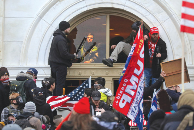  A MOB of supporters of then-US president Donald Trump climb through a window they broke, as they storm the United States Capitol Building in Washington, on January 6, 2021 (credit: LEAH MILLIS/REUTERS)