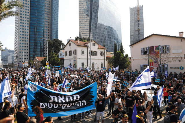  Israelis working in the hi-tech sector hold aloft the Israeli flag and a banner with the Hebrew words ‘The hi-tech protest’ as they demonstrate against proposed judicial reforms on January 24.  (photo credit: CORINNA KERN/REUTERS)