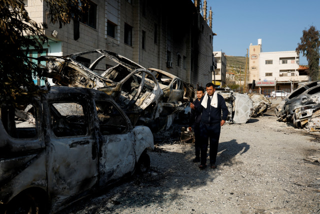  Palestinians walk near cars burned in an attack by Israeli settlers following an incident where a Palestinian gunman killed two Israeli settlers near Huwara in the West Bank, February 27, 2023. (credit: AMMAR AWAD/REUTERS)