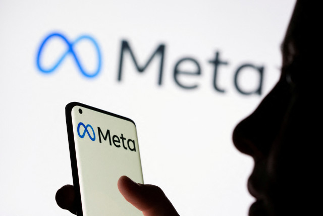 Woman holds smartphone with Meta logo in front of a displayed Facebook's new rebrand logo Meta in this illustration picture taken October 28, 2021. (photo credit: REUTERS/DADO RUVIC/ILLUSTRATION/FILE PHOTO)