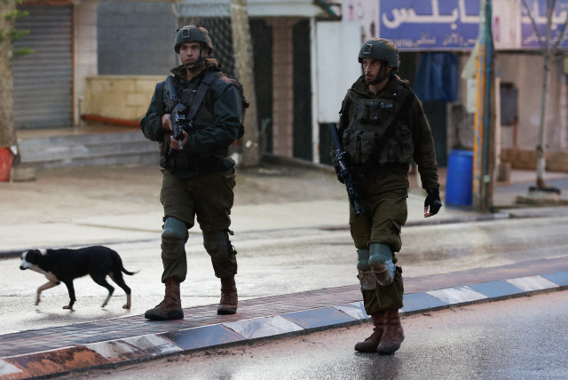  Israeli troops stand guard at the scene of a shooting, in Huwara, in the West Bank, March 19, 2023. (credit: MOHAMAD TOROKMAN/REUTERS)