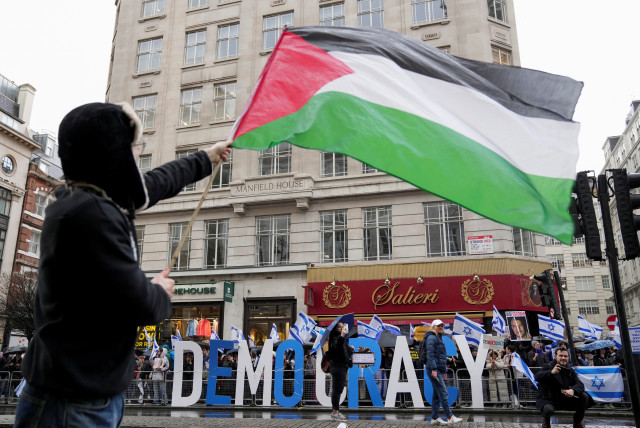 A demonstrator waves a Palestinian flag near demonstrators with Israeli flags during a protest against Israeli Prime Minister Benjamin Netanyahu and the government's judicial reform plans as he visits Britain, in London, Britain March 24, 2023. (credit: REUTERS/Maja Smiejkowska)