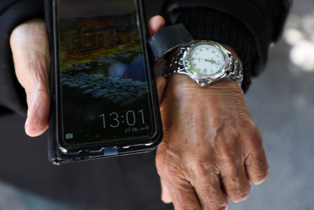 Mohamed al-Arab, a Lebanese Muslim, shows the different timings on his watch and mobile phone, amid a dispute between political and religious authorities over a decision to extend winter time, in Beirut, Lebanon, March 26, 2023. (credit: REUTERS/MOHAMED AZAKIR)