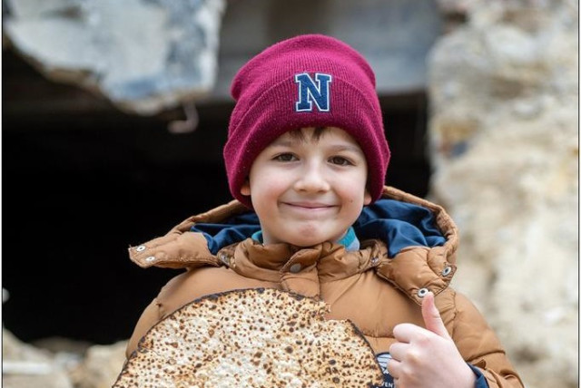  A Ukrainian boy holds up a matzah sent to the Jewish communities in Ukraine. (credit: JRNU)