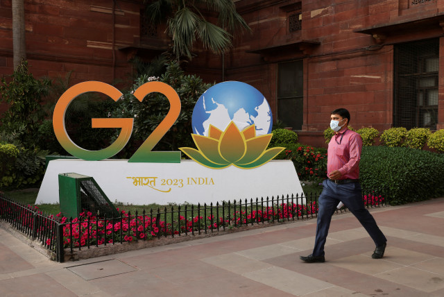  A man walks past a model of G20 logo outside the finance ministry in New Delhi, India, March 1, 2023 (credit: REUTERS)