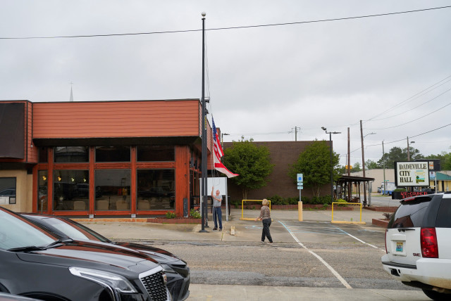  A man lowers the U.S. and Alabama flags to half mast, a day after a shooting at a teenager's birthday party in a dance studio, in Dadeville, Alabama, U.S., April 16, 2023 (credit: REUTERS/Cheney Orr)