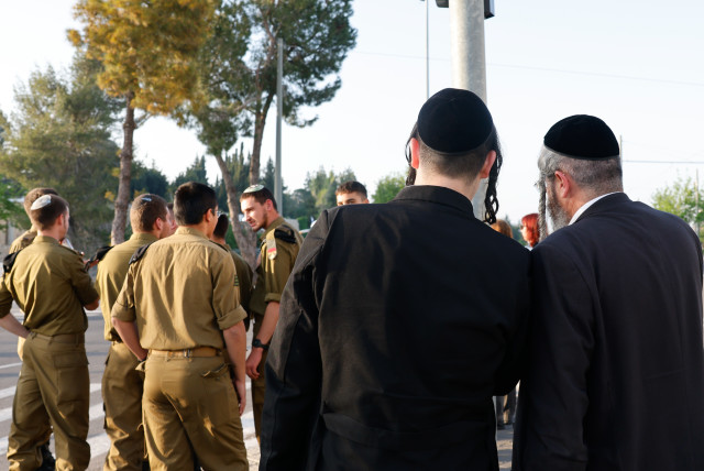  Haredi men dressed in traditional ultra-Orthodox garb stand behind a group of religious IDF soldiers (credit: MARC ISRAEL SELLEM/THE JERUSALEM POST)