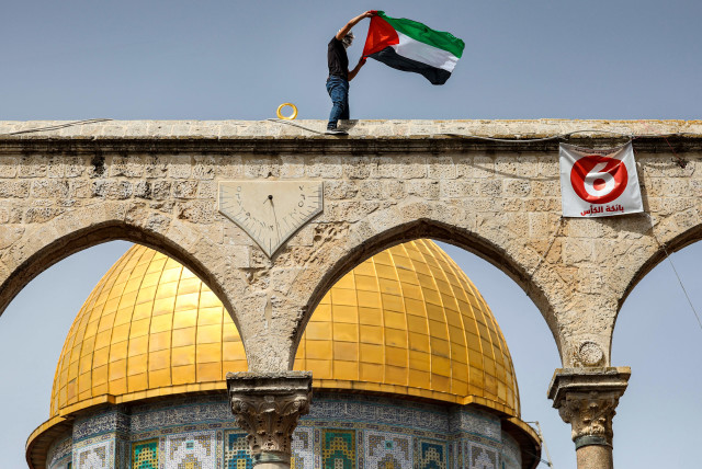  A man waves a Palestinian flag while standing above a sundial along a colonnade before the Dome of the Rock shrine at al-Aqsa mosque compound in the Old City of Jerusalem on April 7, 2023 on the third Friday Noon prayer during the Muslim holy fasting month of Ramadan.  (photo credit:  AHMAD GHARABLI/AFP VIA GETTY IMAGES)