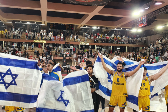 MACCABI TEL AVIV players and fans celebrate with Israeli flags at the Gaston Medecin Arena after the yellow-and-blue beat host AS Monaco 79-67 on Tuesday night in Game 1 of their Euroleague quarterfinal series. (credit: MACCABI TEL AVIV/COURTESY)