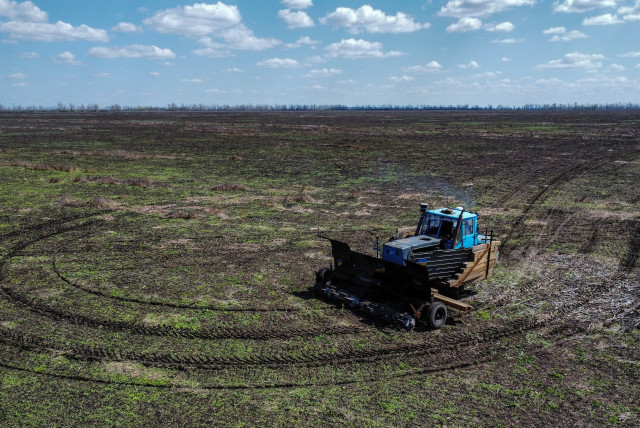 Workers fix a part of a remote controlled demining machine, created by local farmer Oleksandr Kryvtsov with his tractor and armoured plates from destroyed Russian military vehicles near the village of Hrakove, in Kharkiv region, Ukraine April 26, 2023. (credit: REUTERS/Vitalii Hnidyi)