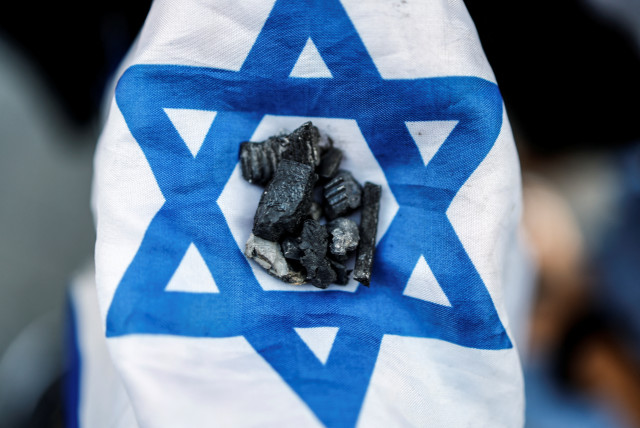  A girl holds up pieces of shrapnel arranged on an Israeli flag after a rocket, launched from Gaza, landed in Sderot, southern Israel, May 2, 2023. (credit: AMIR COHEN/REUTERS)