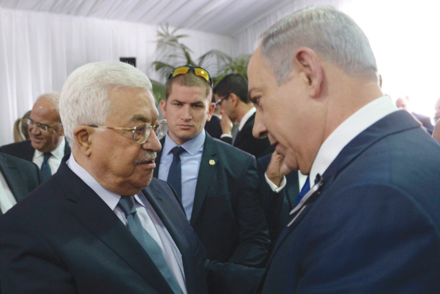  PRIME MINISTER Benjamin Netanyahu and PA head Mahmoud Abbas shake hands at the funeral of Shimon Peres on Mount Herzl, in Jerusalem, in 2016.  (photo credit: AMOS BEN GERSHOM/GPO)