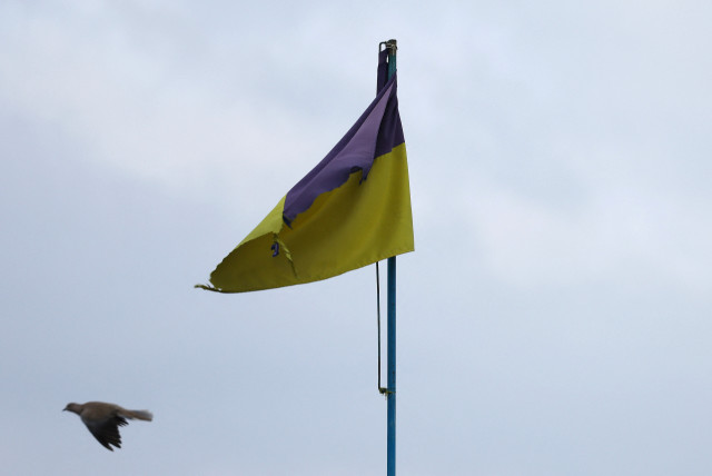  A pigeon flies past a Ukrainian flag on top of the cultural house during heavy fighting at the frontline of Bakhmut and Chasiv Yar, in Chasiv Yar, Ukraine, April 11, 2023.  (credit: KAI PFAFFENBACH/REUTERS)