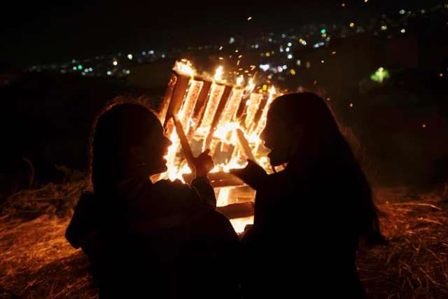 People gather round a bonfire in the Jerusalem neighborhood of Arnona in celebration of the Jewish holiday of Lag Ba'omer, May 8, 2023. (credit: MARC ISRAEL SELLEM/THE JERUSALEM POST)