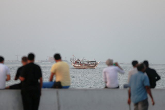  A traditional boat sails towards the port as people relax at a corniche walk in the late hours of the afternoon to beat the summer heat, in Doha, Qatar, September 3, 2021. (credit: REUTERS)
