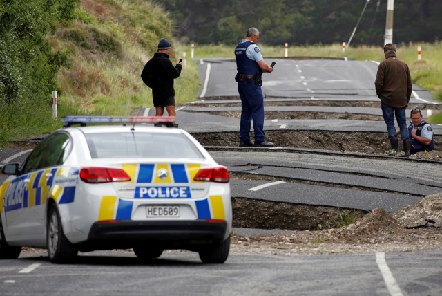  Policemen and locals look at damage following an earthquake, along State Highway One near the town of Ward, south of Blenheim on New Zealand's South Island, November 14, 2016 (credit: REUTERS/ANTHONY PHELPS/FILE PHOTO)
