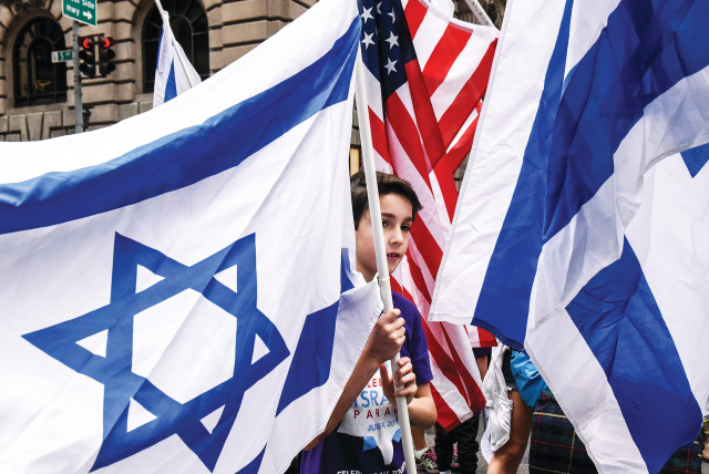  A BOY IS surrounded by Israeli and American flags during a ‘Celebrate Israel’ parade along 5th Ave. in New York City.  (photo credit: STEPHANIE KEITH/REUTERS)