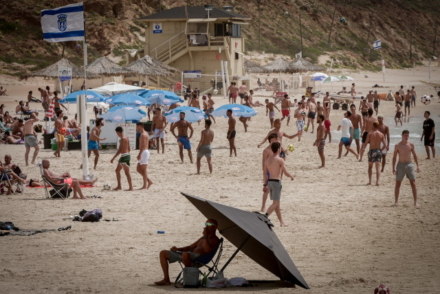  People enjoy at the beach in Herzliya, during a hot weather, on May 22, 2023.  (photo credit: AVSHALOM SASSONI/FLASH90)