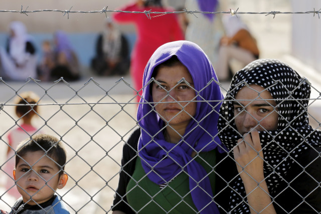  Yazidi refugees stand behind fences as they wait for the arrival of United Nations High Commissioner for Refugees Special Envoy Angelina Jolie at a Syrian and Iraqi refugee camp in the southern Turkish town of Midyat in Mardin province, Turkey, June 20, 2015. (credit: UMIT BEKTAS / REUTERS)